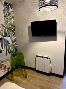 a living room with a tv and a chair and a vase at Le Hameau : Calme et élégant appartement 2 pièces in Rouen