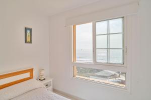 een slaapkamer met een bed en een raam met uitzicht op de oceaan bij VENTANA AL ATLANTICO in El Médano