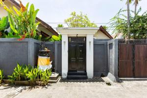 dom z czarnymi drzwiami i płotem w obiekcie Villa Joylen Seminyak Bali w mieście Seminyak