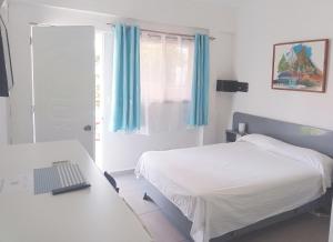 a bedroom with a bed and a desk and a window at Hotel Casa Coco in Boca Chica