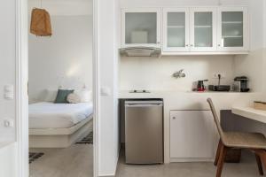 eine kleine weiße Küche mit einem Bett und einem Tisch in der Unterkunft Kleris Apartment 4 Tinos in Tinos + 14 Fotos