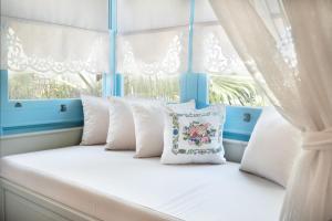 a white bed with white pillows and a window at Bramasole Alaçatı Butik Hotel in Alacati