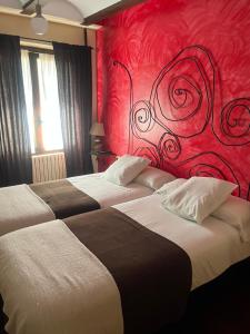 two beds in a hotel room with a red wall at The Garden by LUKE in Ezcaray