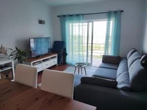 un soggiorno con un divano, un tavolo e una televisione di Zambujal Sun a Sesimbra