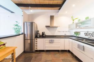 uma cozinha com armários brancos e um frigorífico de aço inoxidável em Paseo Playa em Port de Sóller
