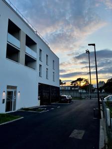 een gebouw met een parkeerplaats met een zonsondergang op de achtergrond bij Appartement de standing avec parking privé in Cherbourg en Cotentin