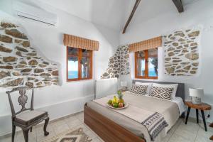 a bedroom with a bed and a chair and windows at Azul Boutique Home in Skiathos