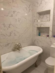 a white bathroom with a tub and a toilet at 15 min drive to airport 20 min to Loch Lomond and city center in Old Kilpatrick