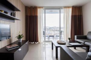 a living room with a couch and a table and a television at Valletta view Apartments by ST Hotels in Il- Gżira