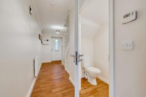 a white bathroom with a toilet and a hallway at 3 Bed House, Sleeps 8 - Contractors, Relocators & Visitors, Parking, Garden, Wi-Fi & Foosball table in Bedford