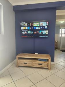 une télévision sur un mur bleu avec une table basse en bois dans l'établissement INNIKOL 55, à Mossel Bay