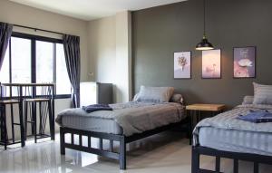 a bedroom with two twin beds and a window at Is Am Are Stay Boutique in Ratchaburi