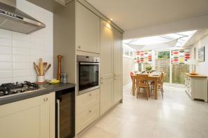 a kitchen with white cabinets and a dining room with a table at Pantiles in Aldeburgh