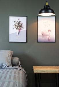 a bedroom with two pictures of a swan and a bed at Is Am Are Stay Boutique in Ratchaburi