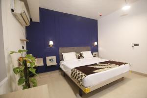 a bedroom with a large bed with a blue wall at Virohaa Garden Hotel in Ghaziabad