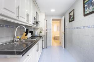 a kitchen with white cabinets and a sink and a hallway at Home2Book Fantastic 160m2 Terrace Flat & BBQ in Radazul