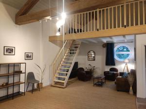 a living room with a staircase in a loft at Le Relais des Cigognes in Marlieux