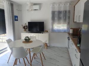 uma cozinha branca com uma mesa e cadeiras brancas em Apartmani Zlata em Sveti Filip i Jakov