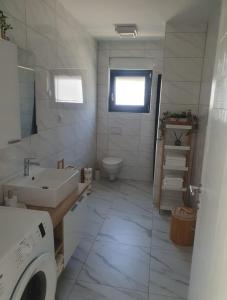 uma casa de banho branca com um lavatório e um WC em Apartmani Zlata em Sveti Filip i Jakov