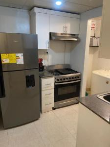 a kitchen with a stainless steel refrigerator and a stove at Hermoso residencial con piscina licey al medio in Licey al Medio