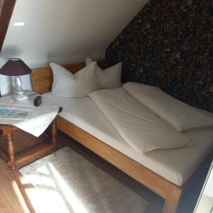 uma cama com lençóis brancos e almofadas ao lado de uma mesa em Zur weißen Rosenblüte, Appartement em Schneverdingen