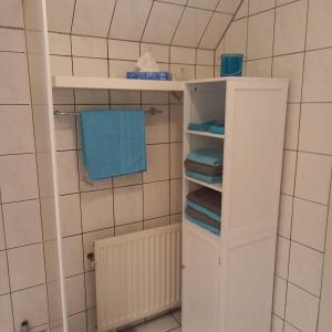 uma casa de banho com uma prateleira branca e toalhas em Zur weißen Rosenblüte, Appartement em Schneverdingen