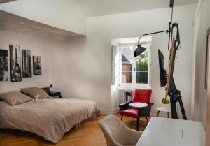 een slaapkamer met een bed en een rode stoel bij Le Clocher de la Duchesse in Bonnelles