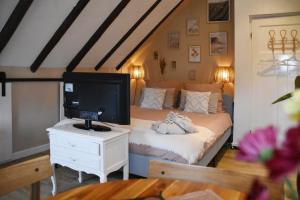 VeendamBed en Breakfast Studio Raif - Authentiek en sfeervol overnachten的一间卧室，有一张床，桌子上有一台电视