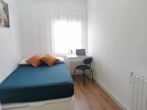 a bedroom with a bed and a desk with a laptop at Bonito Ático in Terrassa