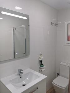 a white bathroom with a sink and a toilet at Bonito Ático in Terrassa