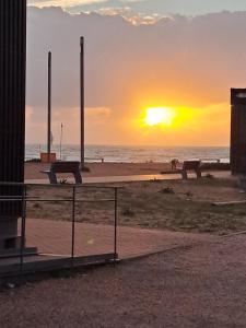 a sunset on the beach with benches on the beach at Apart Praia da Costa da Caparica in Costa da Caparica