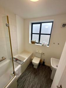 a bathroom with a toilet and a sink and a window at Reading City Centre - Business - Relocation - Luxury Apartment in Reading