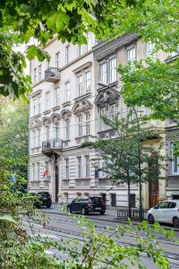 a large white building with cars parked in front of it at Hotel Maximum in Krakow