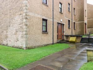 a brick building with a yellow chair in front of it at The Kate Kennedy Apartment in St Andrews