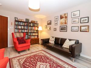 a living room with a leather couch and a red chair at The Kate Kennedy Apartment in St Andrews