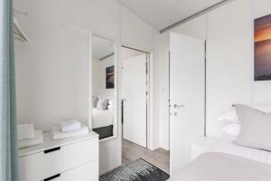 a white bedroom with a bed and a mirror at Upper Cliff Studio in Portland