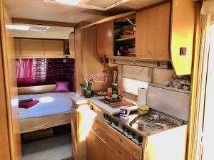 a small kitchen with a bed in a trailer at Caravan on the beach, pet friendly in Corbu