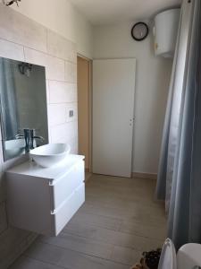 ein weißes Badezimmer mit einem Waschbecken und einem Spiegel in der Unterkunft Suite parentale Villa au bord de la mer chez Saloua in Bouéni