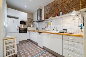 une cuisine avec des placards blancs et un mur en briques dans l'établissement Hauzify I Casa d'Anselm Clavé, à Calella
