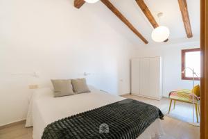 een witte slaapkamer met een bed en een stoel bij Mediterranean Way - Talavera in Tarragona