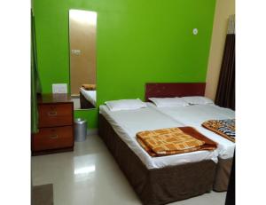 a bedroom with a bed and a green wall at Hotel Shree, Somnath in Somnath
