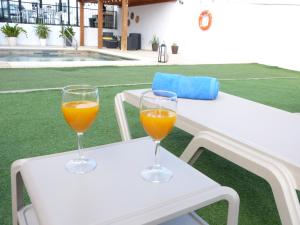 Dois copos de sumo de laranja sentados numa mesa branca. em Villa Alto Arena piscina privada climatizada em Ingenio