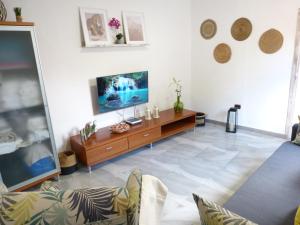 uma sala de estar com uma televisão de ecrã plano na parede em Villa Alto Arena piscina privada climatizada em Ingenio