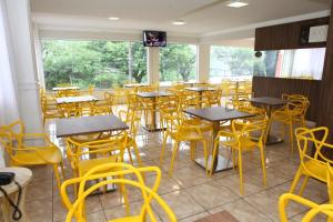 um restaurante com mesas e cadeiras amarelas num quarto em HOTEL JOINVILLENSE em Joinville