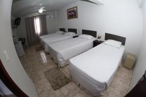 Cette chambre comprend 3 lits et une télévision. dans l'établissement HOTEL JOINVILLENSE, à Joinville