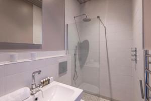 La salle de bains blanche est pourvue d'une douche et d'un lavabo. dans l'établissement The Cleveland Arms IV, à Londres