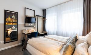 Cette chambre comprend un lit, un bureau et une télévision. dans l'établissement YORS Boutique Hotel, à Hanovre