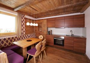 a kitchen with a wooden table and purple chairs at GMS Holidays in Katschberghöhe