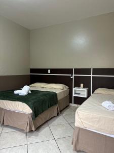 a room with two beds and a tiled floor at Pousada Santa Terezinha in Garopaba