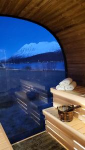 a view of a snow covered mountain through a window at Idyllisk hus med sauna og jacuzzi, Lyngen in Nord-Lenangen